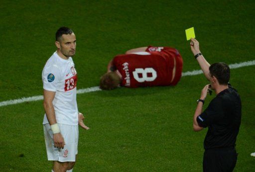 Polish defender Marcin Wasilewski (L) is given a yellow card