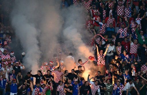 Fans of Croatia react as smoke of a flare billows in the grandstand during the Euro 2012 match Italy vs Croatia