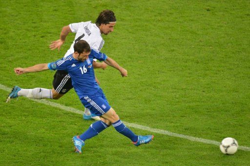 Greek midfielder Giorgos Fotakis clashes with German midfielder Sami Khedira (top)