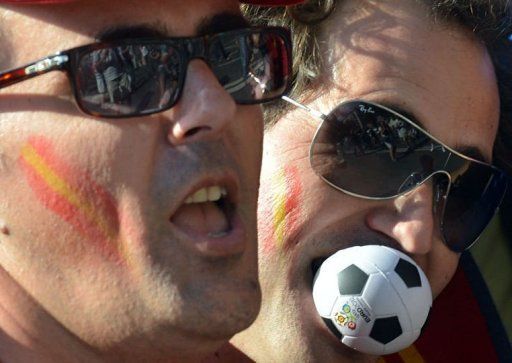 A Spanish fan bites a small football in the fan zone of Kiev