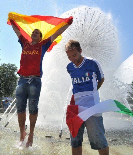 An Italian and a Spanish football fan cool themselves in a fountain in the fan zone