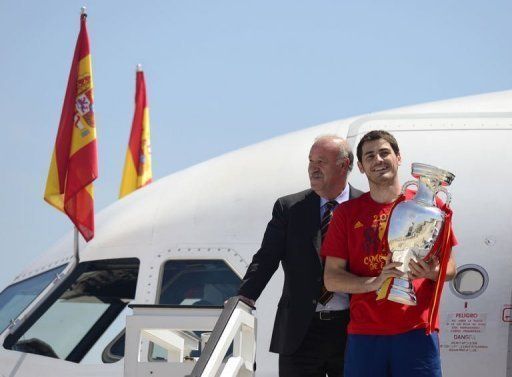 Iker Casillas holds the Euro 2012 trophy alongside coach Vicente del Bosque at Madrid-Barajas airport