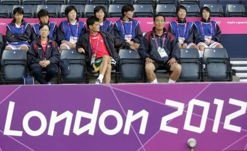 North Korea's coach Gun Sin Ui (C) waits for his team's delayed group G women's match