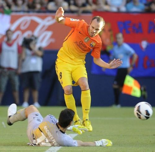 Barcelona's Andres Iniesta (R) vies for the ball with Osasuna's goalkeeper Andres Fernandez (L)