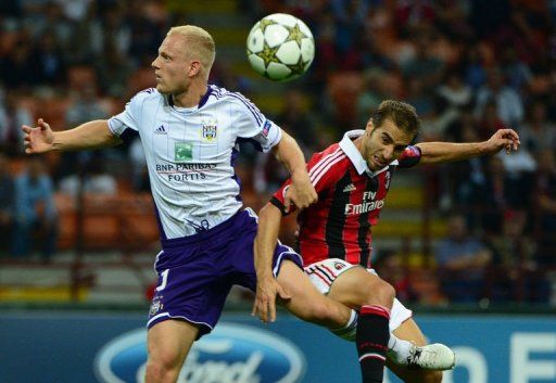 Anderlecht&#039;s defender Olivier Deschacht (L) jumps for the ball with AC Milan&#039;s midfielder Mathieu Flamini