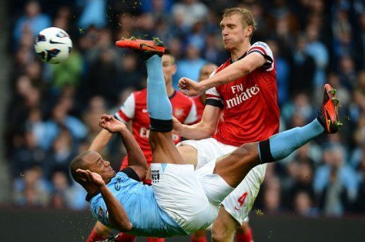 Manchester City&#039;s Vincent Kompany (L) attempts an overhead kick as Arsenal&#039;s Per Mertesacker stands clear