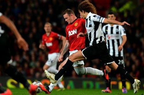 Manchester United's Wayne Rooney (C) vies for the ball with Newcastle United's Fabricio Coloccini