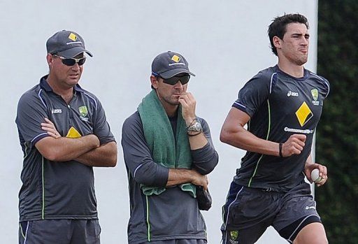 Australia&#039;s Mitchell Starc (R) delivers a ball as coach Mickey Arthur (L) and batting coach Justin Langer look on