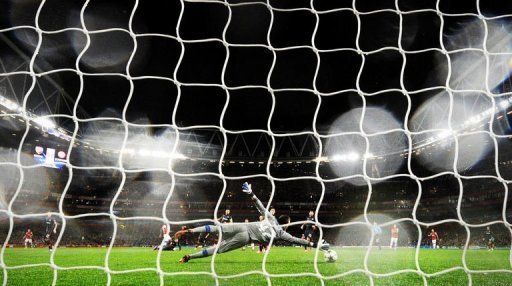 Olympiakos FC&#039;s goalkeeper Balazs Megyeri (C) dives to try and save a shot from Arsenal&#039;s Gervinho