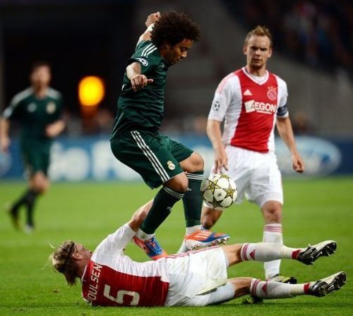 Real Madrid's Marcelo (C) jumps over Ajax Amsterdam's Christian Poulsen