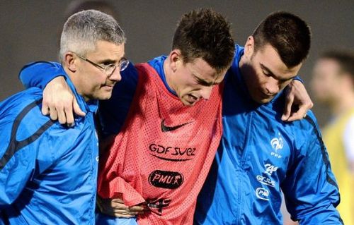 Laurent Koscielny (C) receives medical assistance during a training session in Clairefontaine-en-Yvelines