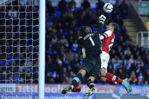 Reading's goalkeeper Adam Federici (L) clears the ball under pressure from Arsenal's Marouane Chamakh