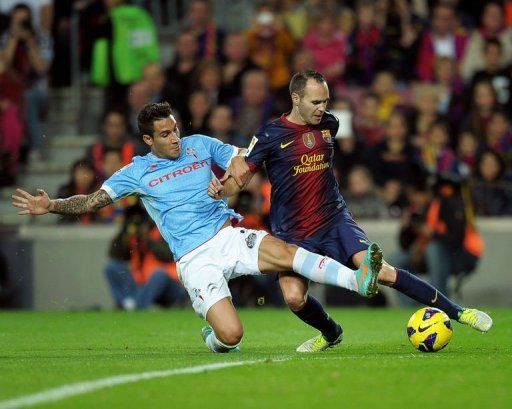 Barcelona&#039;s midfielder Andres Iniesta (R) clashes with Celta&#039;s defender Hugo Mallo