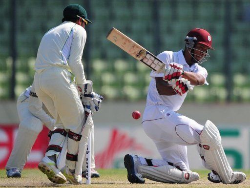 Kieran Powell (right) plays a shot as  Bangladesh captain Mushfiqur Rahim reacts