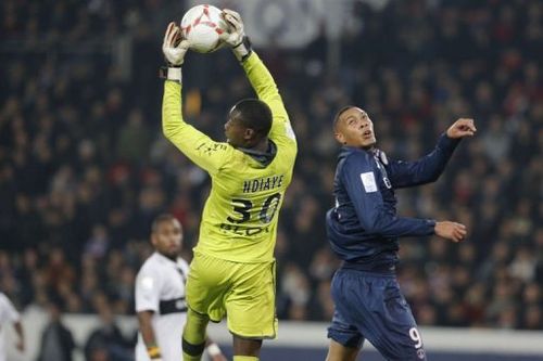 Rennes' goalkeeper Cheik Ndiaye (L) grabs the ball in front of Paris Saint-Germain's forward Guillaume Hoarau