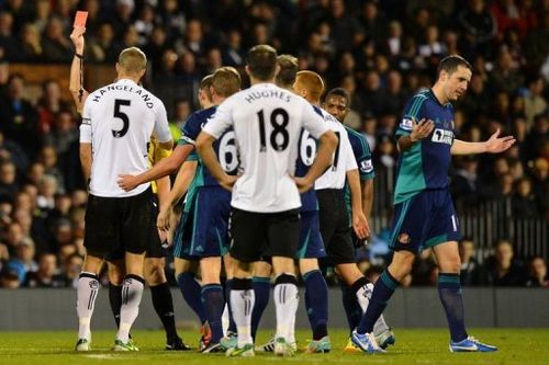 Fulham's Brede Hangeland (L) receives a straight red card from referee Lee Probert