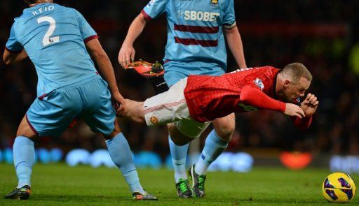 Manchester United&#039;s Wayne Rooney (R) falls as he fights for the ball with West Ham United&#039;s Winston Reid (L)