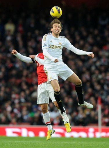 Swansea City&#039;s midfielder Miguel Michu (R) beats Arsenal&#039;s defender Thomas Vermaelen (L) for a high ball