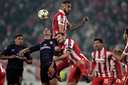 Olympiakos&#039; Kostas Mitroglou (top) and Vassilis Torosidis (C) fight for the ball with Arsenals&#039;s Marouane Chamakh