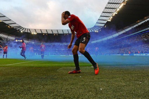 Rio Ferdinand reacts after being struck by a coin