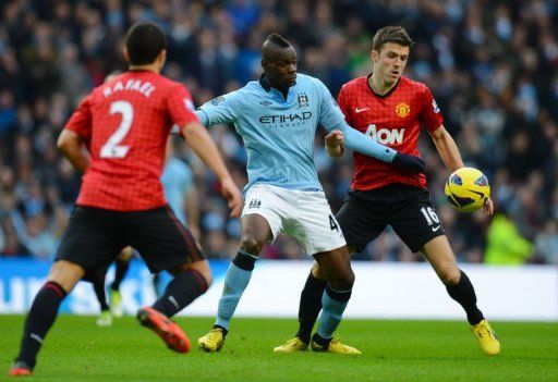 City&#039;s Mario Balotelli (C) vies with United&#039;s Michael Carrick (R)