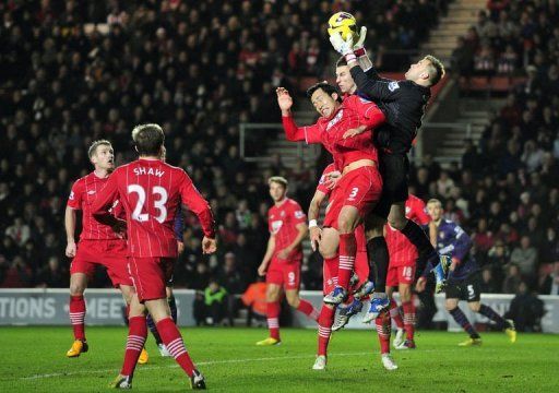 Southampton goalkeeper Artur Boruc (R) claims the ball under pressure from Laurent Koscielny on January 1, 2013