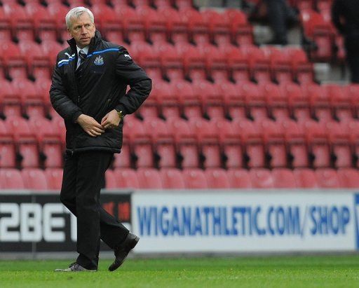 Newcastle United manager Alan Pardew walks past rows of empty seats at Wigan Athletic&#039;s DW Stadium on April 28, 2012