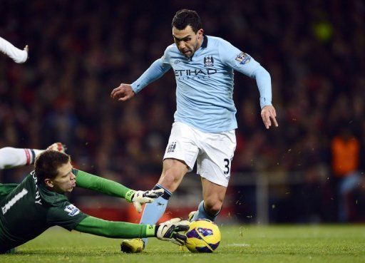 Carlos Tevez (R) is challenged by Arsenal goalkeeper Wojciech Szczesny during a game in London on January 13, 2013