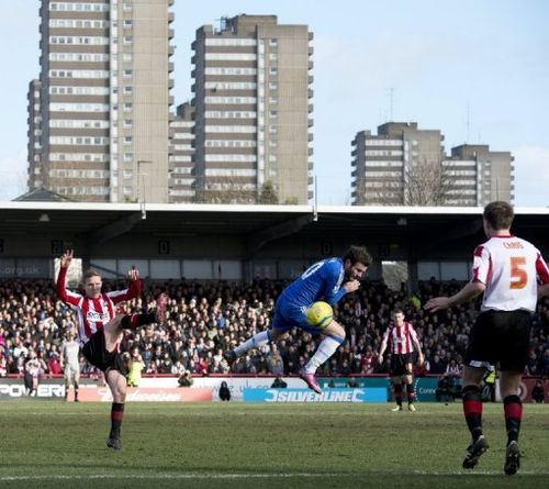 Chelsea's Juan Mata (C) tries to block a shot from Brentford's Adam Forshaw (L) during their match on January 27, 2013