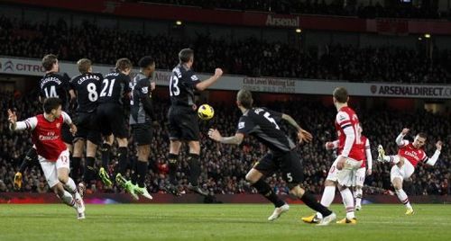 Arsenal's Lukas Podolski (R) takes a free kick at the Liverpool goal in London on January 30, 2013