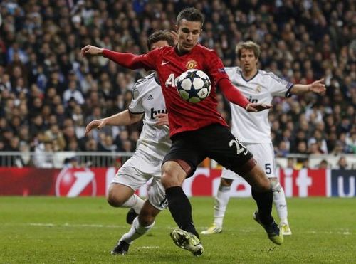 Manchester United's Robin van Persie keeps Real Madrid players at bay during the match  in Madrid on February 13, 2013