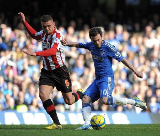 Chelsea&#039;s Juan Mata (right) shoots past Brentford&#039;s Harlee Dean to score the opening goal on February 17, 2013