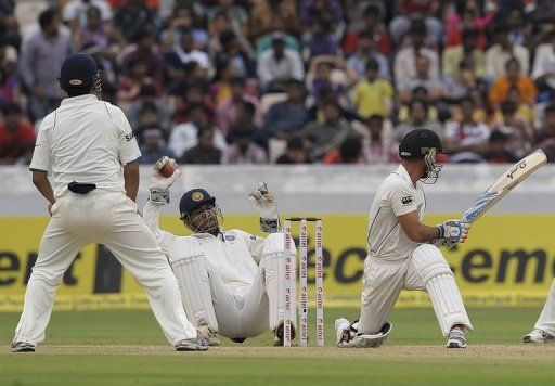 Mahendra Singh Dhoni (centre) catches the ball as New Zealand&#039;s Kruger Van Wyk turns in Hyderabad on August 26, 2012