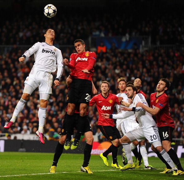 MADRID, SPAIN - FEBRUARY 13:  Cristiano Ronaldo of Real Madrid and Robin van Persie of Manchester United go up for a header during the UEFA Champions League Round of 16 first leg match between Real Madrid and Manchester United 