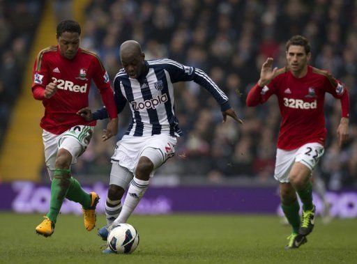 West Brom&#039;s Youssouf Mulumbu (C) runs against Swansea&#039;s Jonathan de Guzman (L) and Angel Rangel, March 9, 2013