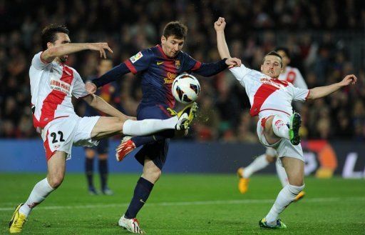 Lionel Messi (C) is blocked by Rayo Vallecano&#039;s Jordi Figueras Montel (L) and Tito during their match on March 17, 2013