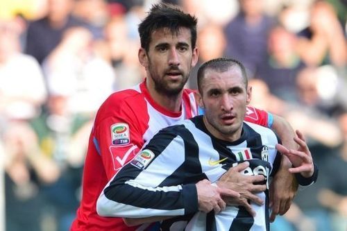 Juventus' Giorgio Chiellini is held by Catania defender Nicolas Spolli during the sides' Serie A match on March 10, 2013