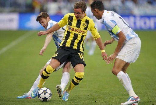 Borussia Dortmund midfielder Mario Goetze (C) dribbles past Malaga&#039;s Welington (R) and Antunes on April 3, 2013