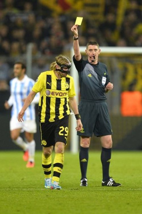 Craig Thomson issues a yellow card to Dortmund's Marcel Schmelzer at the match against Malaga on April 9, 2013