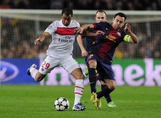 PSG&#039;s Lucas Moura (L) is tackled by with Barcelona&#039;s Xavi Hernandez at Camp Nou stadium on April 10, 2013