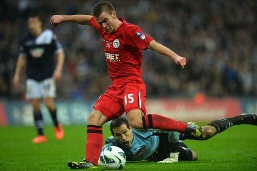 Wigan Athletic's Callum McManaman shoots to score as Millwall's goalkeeper David Forde (down) looks on, April 13, 2013