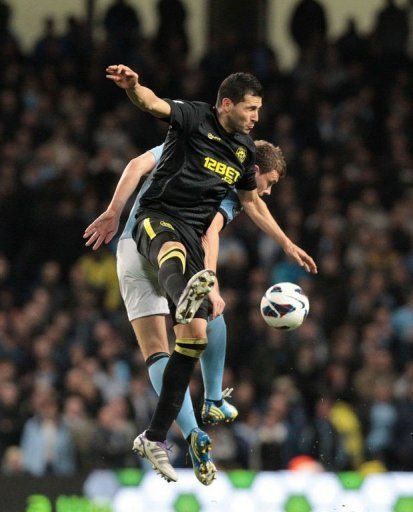 Manchester City&#039;s Edin Dzeko (R) goes for a high ball against Wigan&#039;s Antolin Alcaraz on April 17, 2013