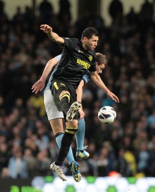 Manchester City's Edin Dzeko (R) goes for a high ball against Wigan's Antolin Alcaraz on April 17, 2013