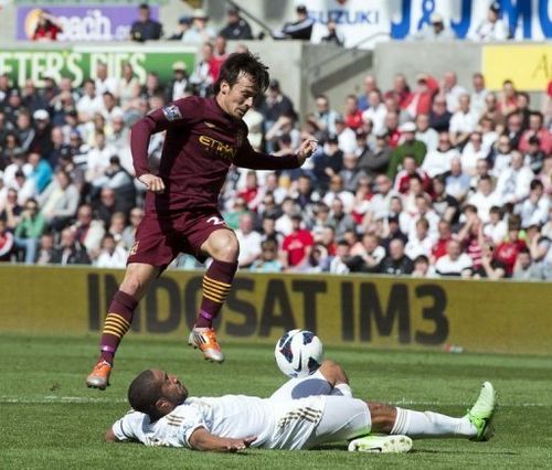 Swansea City's Ashley Williams (bottom) blocks a shot from Manchester City's David Silva in Swansea, on May 4, 2013