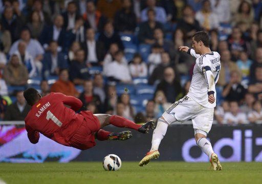 Malaga&#039;s goalkeeper Carlos Kameni dives for the ball at the feet of Real Madrid&#039;s Cristiano Ronaldo on May 8, 2013
