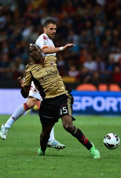 AC Milan's Mario Balotelli  (R) fights for the ball with AS Roma's Simone Perrotta in Milan on May 12, 2013