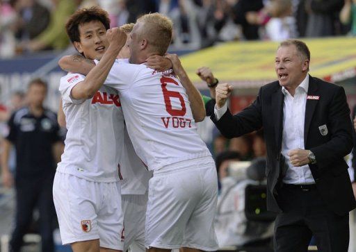 L-R: Augsburg&#039;s Dong-Won Ji,  Kevin Vogt and manager Stefan Reuter celebrate in Augsburg, on May 18, 2013