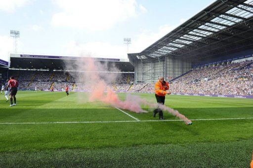 A steward removes a smoke bomb at The Hawthorns on May 19, 2013