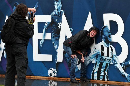 A woman poses next to a billboard bearing pictures of Dortmund players in Trafalgar Square in London on May 24, 2013