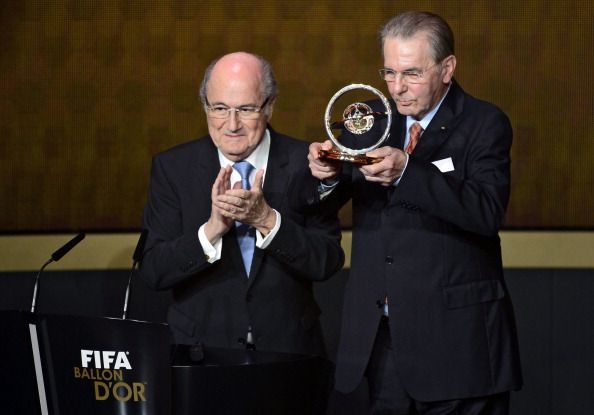 FIFA president Sepp Blatter applauds next to former International Olympic Committee (IOC) president Jacques Rogge (R) after he received the 2013 FIFA Presidential Award 